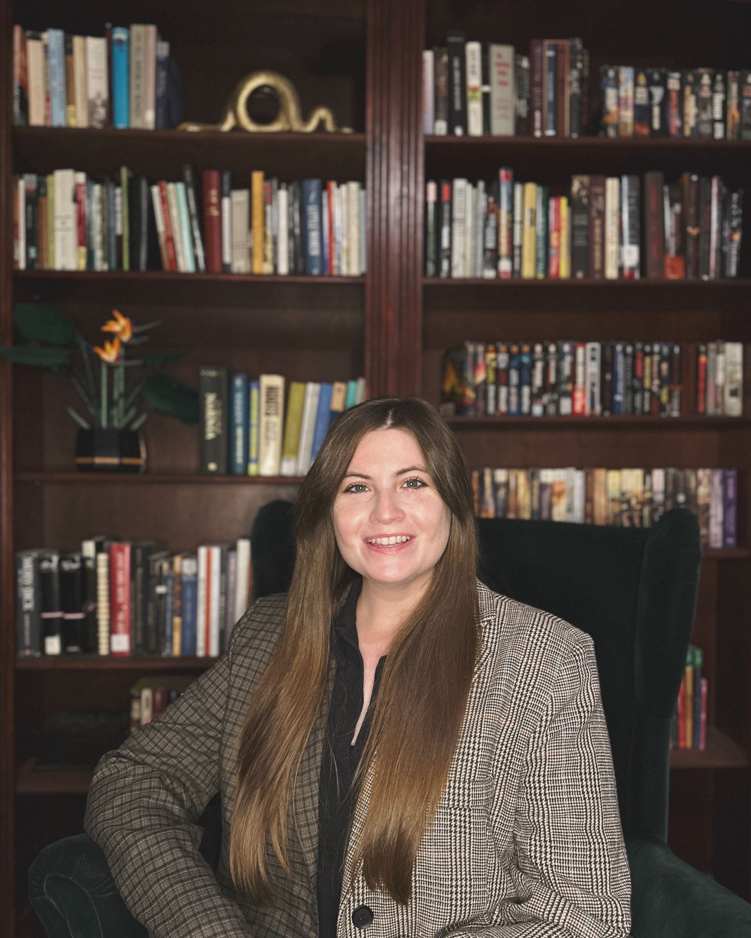 Dr. Smith, a brunette woman, sits in front of her home bookshelf